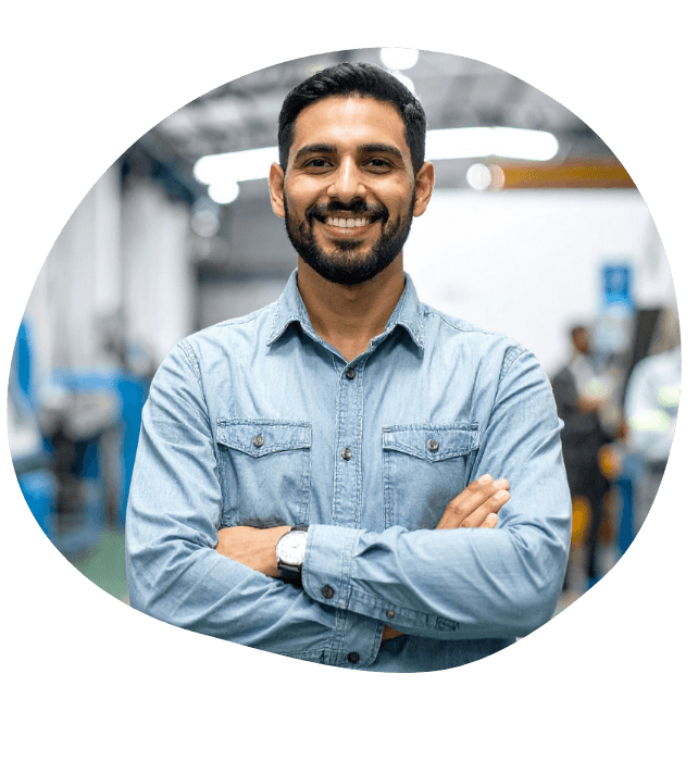 A man in a denim shirt smiling with his arms crossed